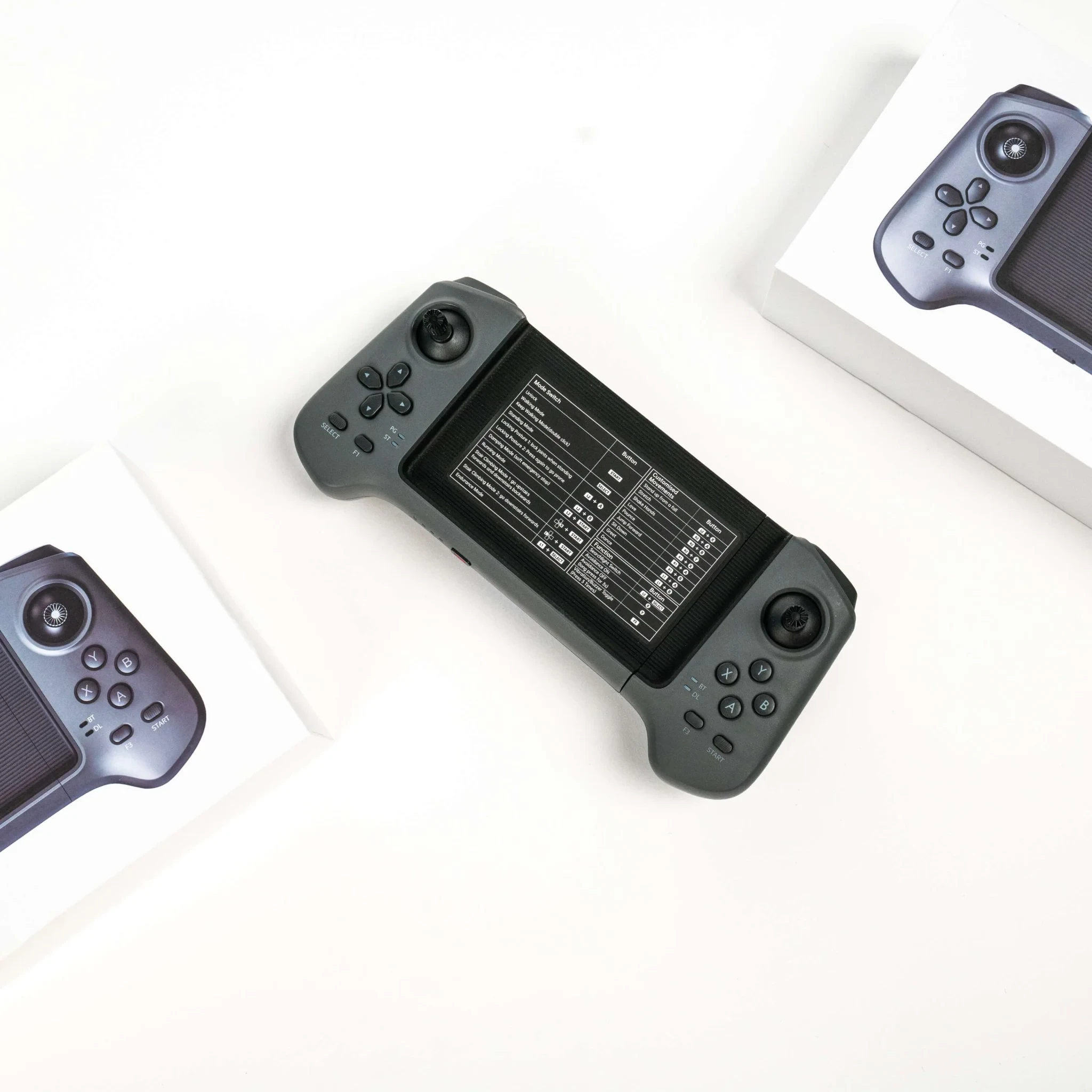 Unitree G1 remote controller on a white surface beside its retail box, showing the two-handed layout with dual joysticks and the mode-switch reference table printed on the center panel